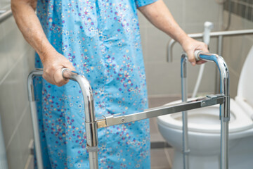 Asian elderly woman patient use walker and toilet bathroom handle security in nursing hospital,...