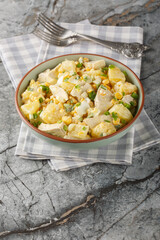Chicken salad with pineapple, corn, cheese, eggs and onions dressed with mayonnaise close-up in a plate on the table. Vertical