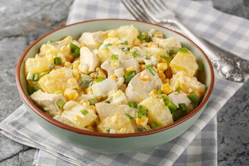 Chicken pineapple salad with corn, cheese, eggs and onions dressed with mayonnaise close-up in a plate on the table. Horizontal