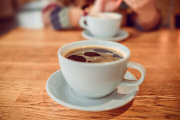 Two cups of coffee resting on a wooden table, representing a cozy coffee break moment in a comfortable setting.