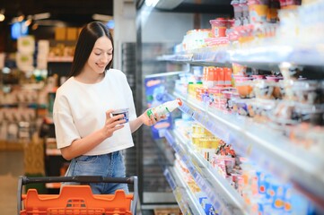 Young satisfied fun woman in casual clothes shopping at supermaket store with grocery cart