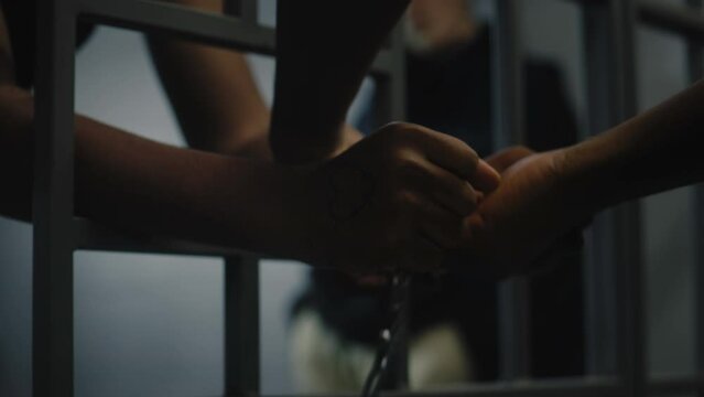 Warden takes off handcuffs from young prisoner. Multi ethnic teenagers serve imprisonment term in correctional facility or detention center. Young inmates in prison cell. Justice system. Close up.
