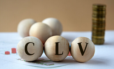 CLV - abbreviation on wooden balls on a background of coins and graphics.