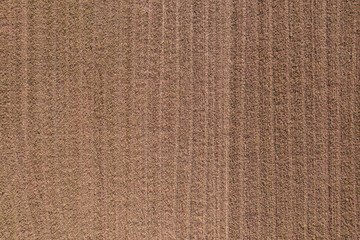  Drone view captures the rhythmic patterns of a plowed field, showcasing textures and lines in wide, open spaces.
