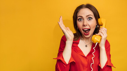 Portrait photo of an emotional smiling girl holding a retro yellow telephone receiver and talking in isolation against a bright yellow background. A place for your text. - obrazy, fototapety, plakaty