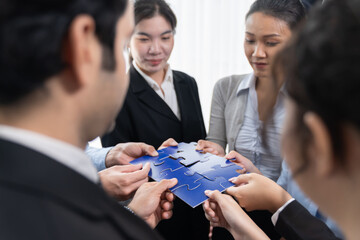 Multiethnic business people holding jigsaw pieces and merge them together as effective solution...