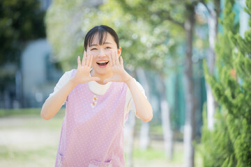 Fototapeta premium 笑顔でカメラ目線の保育士や介護士のイメージ お～いと呼ぶイメージ 転職や採用、求人のイメージにも