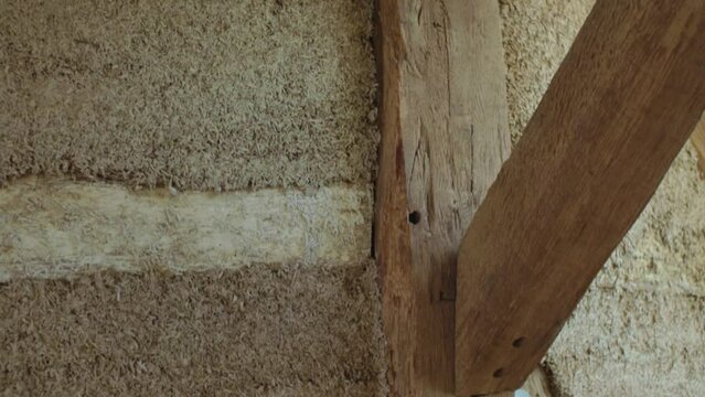Close-up vertical panning down over hempcrete wall with timber frame during construction