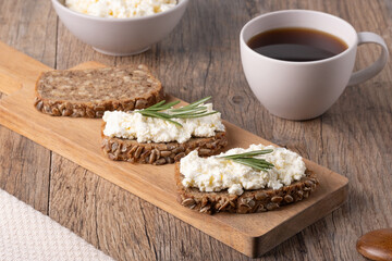 Homemade rye bread with cottage cheese in a plate and coffee. Healthy breakfast concept