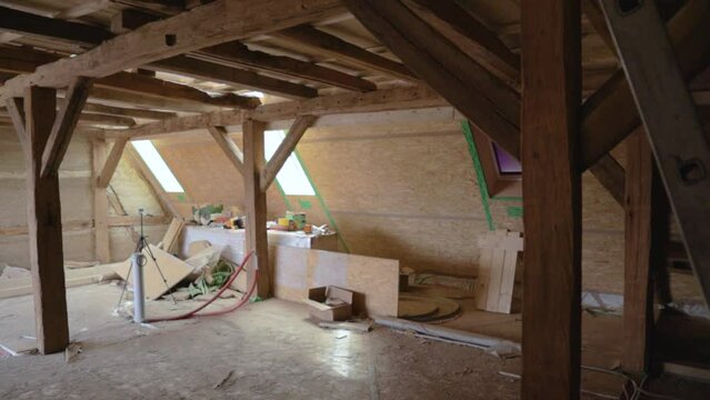 Interior attic construction site with hempcrete wall and visible timber frames, panning left to right