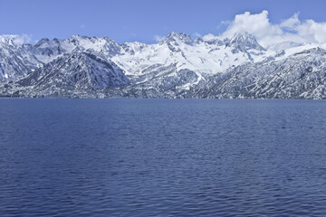 Mountain Lake under Blue Sky in Winter Landscape with Snowy Peaks and Forest