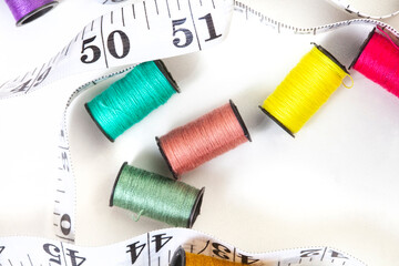 collection of various spools of colorful sewing thread on white, with copy space