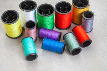 collection of colorful sewing thread on grey, with copy space

