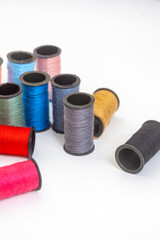 collection of various spools of colorful sewing thread on white, with copy space