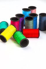 collection of various spools of colorful sewing thread on white, with copy space