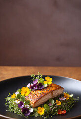 Grilled salmon fillet with edible flowers and microgreens.