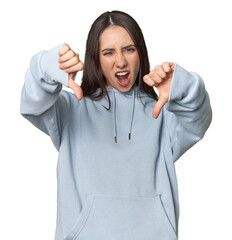Modern young Caucasian woman portrait on studio background showing thumb down and expressing dislike.