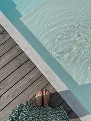 Photo sur Plexiglas Spa Female feet at poolside. Swimming pool with clear blue water with sunlight shadow reflections on waves. Minimal aesthetic summer vacation concept background