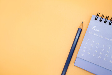 June Calendar and pencil isolated on orange background, planning for business or travel planning...