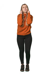 Fototapeta premium Studio portrait of a blonde Caucasian woman covering ears with fingers, stressed and desperate by a loudly ambient.