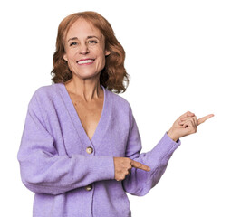Redhead mid-aged Caucasian woman in studio excited pointing with forefingers away.