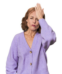 Redhead mid-aged Caucasian woman in studio forgetting something, slapping forehead with palm and closing eyes.