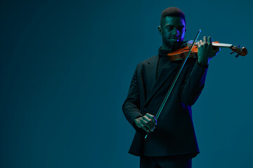 Elegant man in suit playing violin on blue background with copy space for design concept