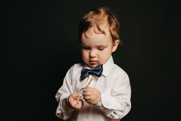 portrait of a small boy on a dark background in a white shirt and bow tie