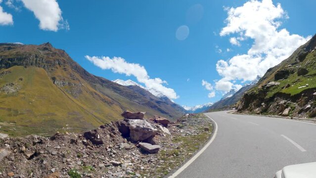 4K shot of scenic road in the Himalayas during the sunny day with blue sky and clouds above the mountains at Rohtang Pass near Manali in Himachal Pradesh, India. Beautiful roads of Rohtang Pass.