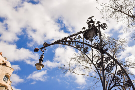 stylish artistic street lamp in barcelona against a blue sty with clouds