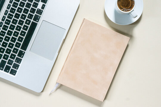 bright feminine banner or header with a stylish workspace with laptop computer, modern office accessories and a small notebook on a blush table, top view, flat lay