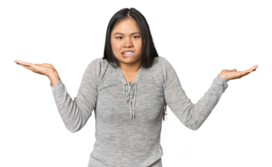 Young chinese woman isolated confused and doubtful shrugging shoulders to hold a copy space.