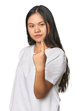 Young chinese woman isolated pointing with finger at you as if inviting come closer.