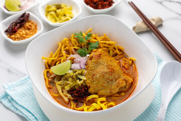 Chicken khao soi, rice noodle with chicken curry, a popular dish from northern Thailand. Flat or round egg rice noodle topped with chicken, vegetables and poured with savory curry.