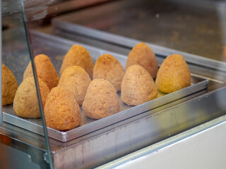 Arancini (deep fried rice balls with meat) Typical Sicilian street food at market in Italy