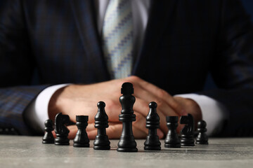 A man in a black suit with chess on the table