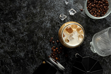 Glass with iced coffee, coffee maker and coffee bean on gray background, space for text