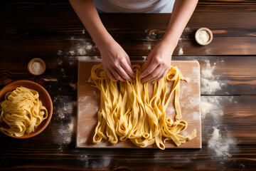 Woman making fettuccine noodles on wooden table top view, close up 