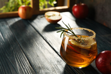 Glass with apple cider and apples on wooden table on light background, space for text