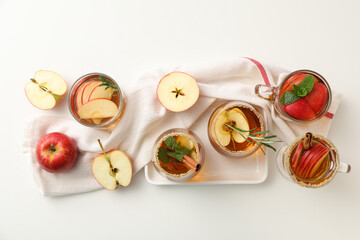 Glasses with apple cider and apples on towel on white background, top view