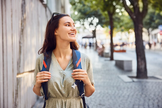 Happy young woman walking with backpack on footpath
