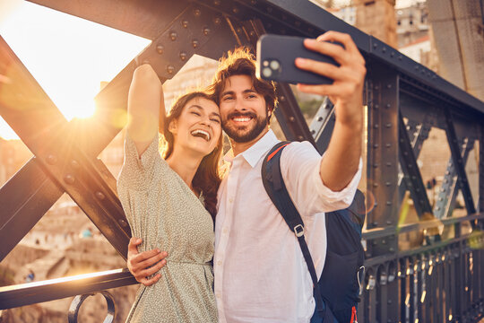 Cheerful couple taking selfie through smart phone at Dom Luis bridge, Porto, Portugal