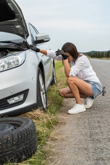 woman driver looking under bonnet of car, broken auto during trip