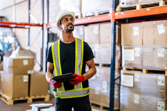 Smiling worker examining inventory with tablet PC at warehouse