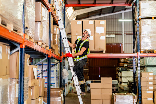 Worker climbing on ladder and reaching for boxes