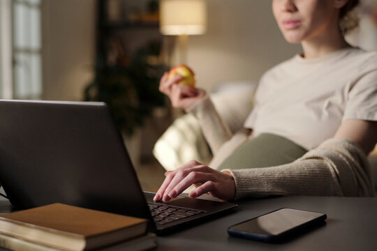 Expecting mother having apple and using laptop in home office