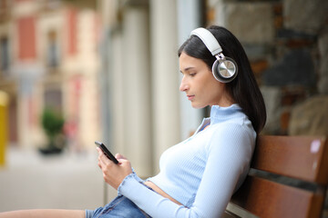 Relaxed woman using phone and headphone in the street - 761245735
