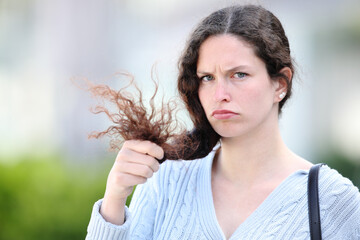 Disappointed woman holding hair looking at you - 761245744