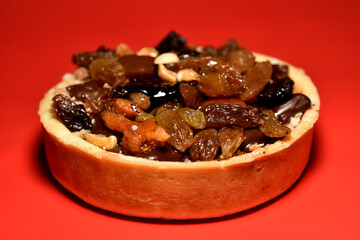 Round cake with cream, nuts and raisins on top.