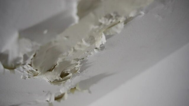 Extreme close up as camera moves across dry ceiling paint as it is peeling off. Ceiling with water leakage or deteriorating wall caused by condensation or moisture in wash room or shower in winter